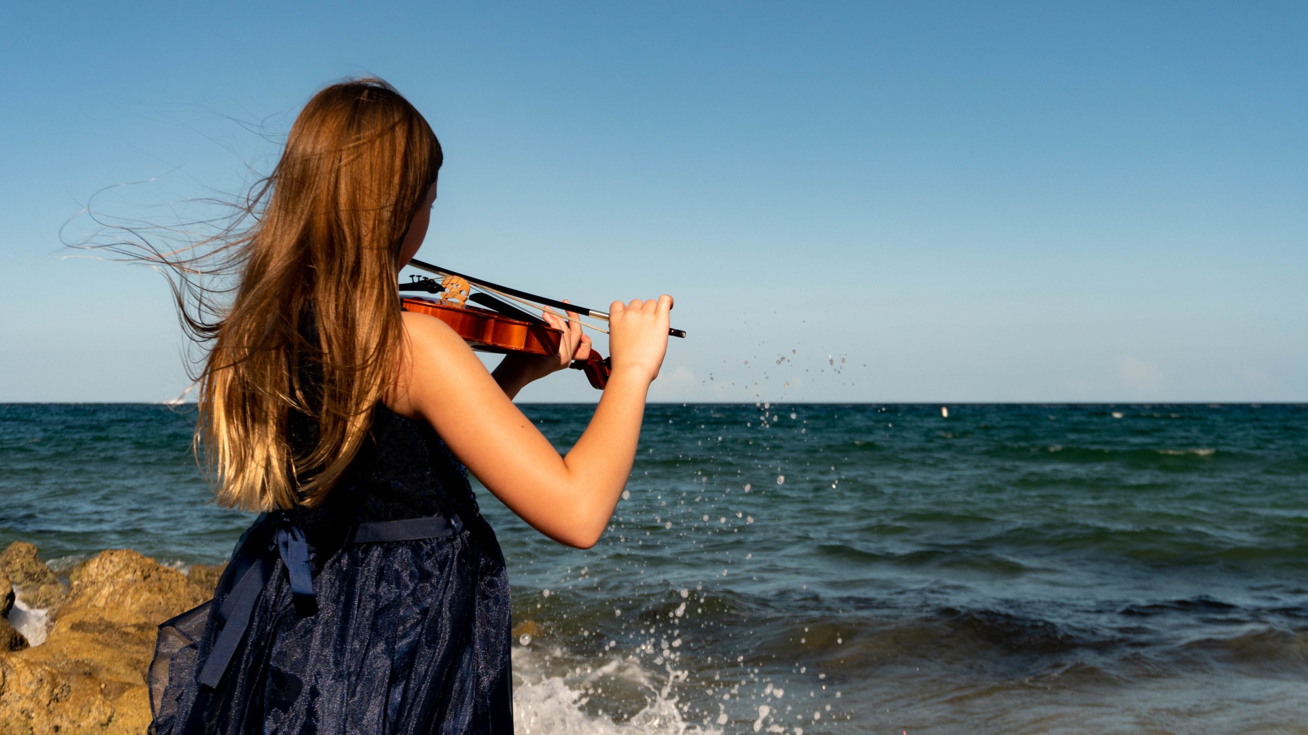 violin student in front of the ocean.